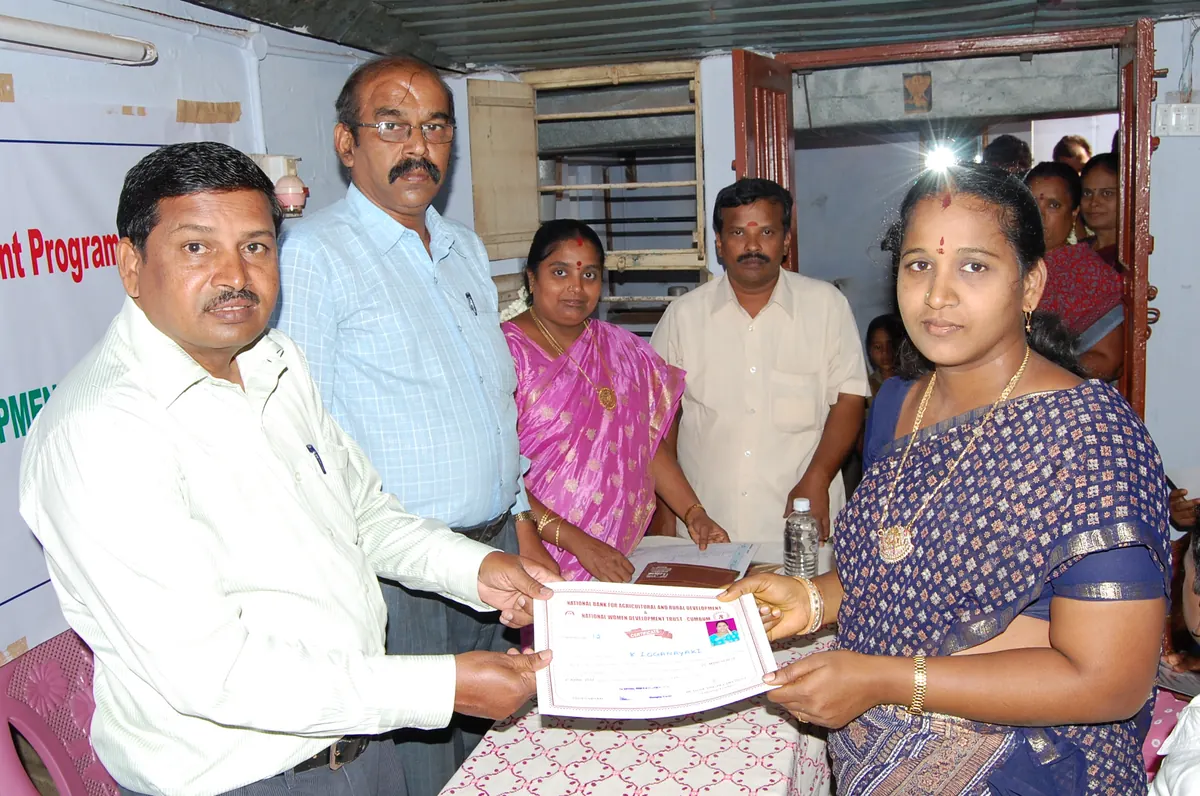 Official presenting a vocational training completion certificate to a woman member